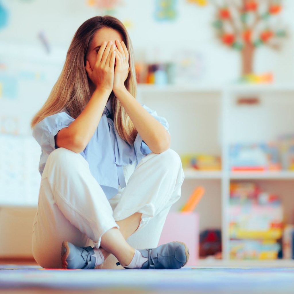 Overwhelmed mom sitting on the ground thinking her ADHD child ruined her life